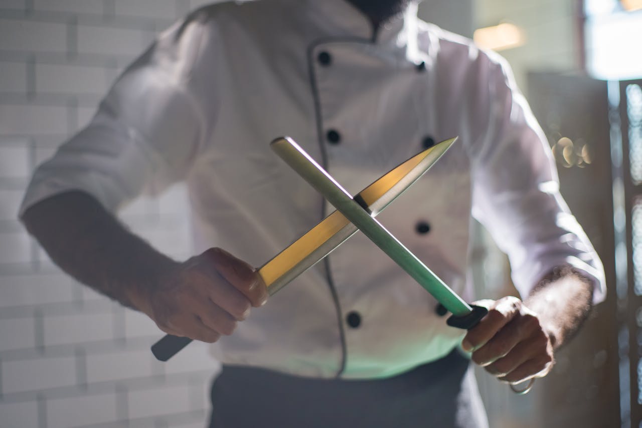 Close-up of a chef sharpening knives, emphasizing culinary skill and precision.